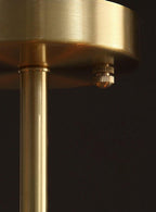 Close view of the brushed brass ceiling plate and rod of this Clérachic chandelier, with a small brass screw below the plate.