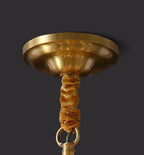 Close view of the domed brass canopy and gold-brown fabric chain cover where this Clérachic chandelier meets the ceiling.