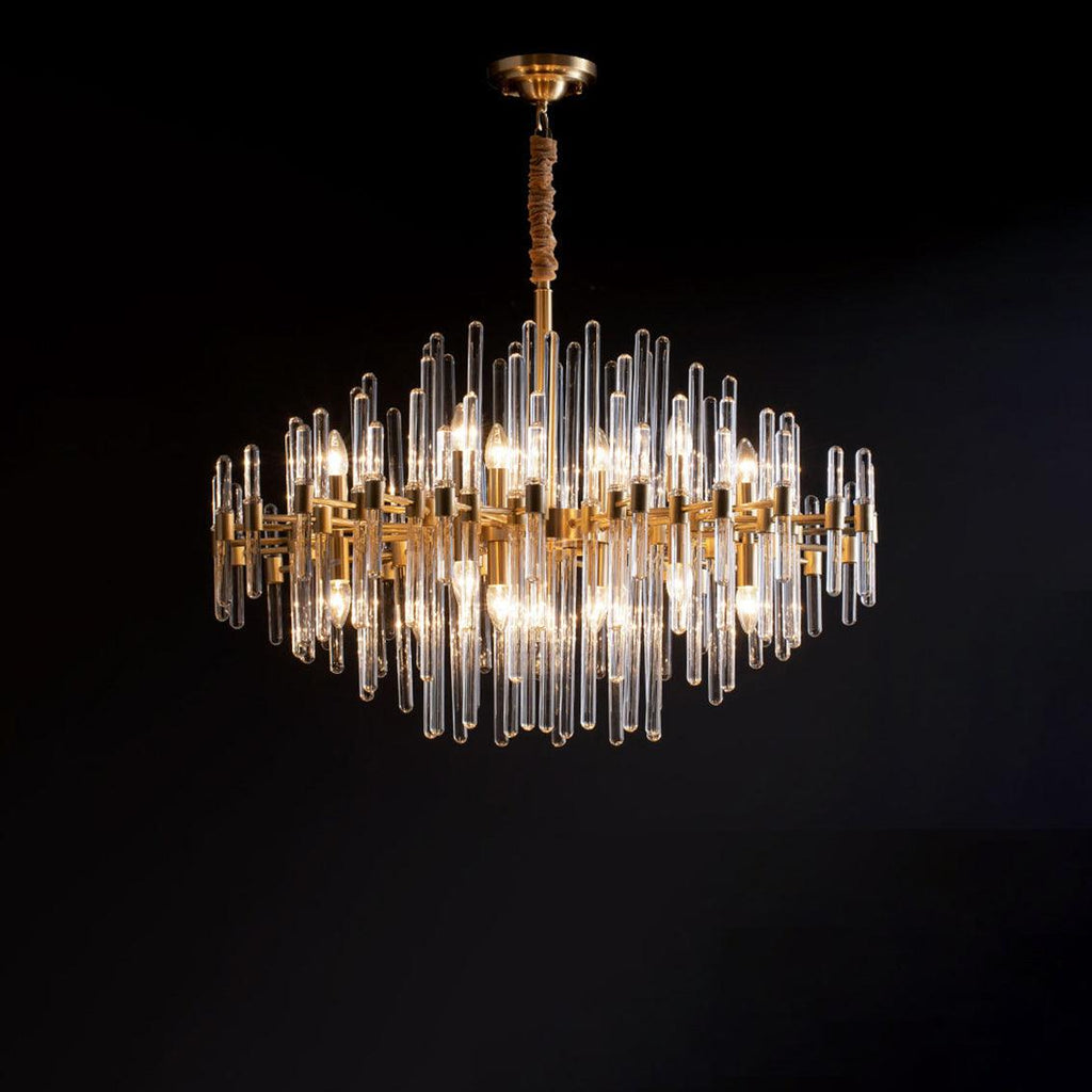 Against a black backdrop, this Clérachic chandelier shows glowing bulbs inside tiers of clear glass rods and brass bars.