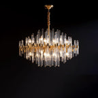 Against a black backdrop, this Clérachic chandelier shows glowing bulbs inside tiers of clear glass rods and brass bars.