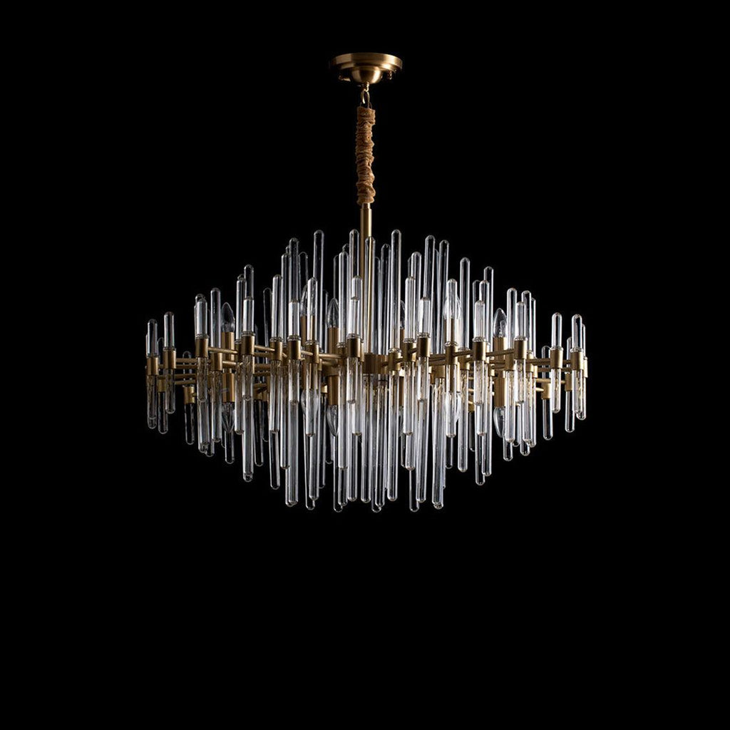 A Clérachic brass chandelier with clear glass rods on black, its rods unlit so the glass shows pale against the dark.