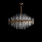 A Clérachic brass chandelier with clear glass rods on black, its rods unlit so the glass shows pale against the dark.