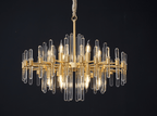 Close, wide view of this Clérachic chandelier on black, with candle-style bulbs among the clear glass rods and brass arms.