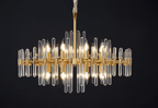 Wide Clérachic chandelier on a black backdrop, a row of candle-style bulbs sitting between upper and lower layers of glass rods.