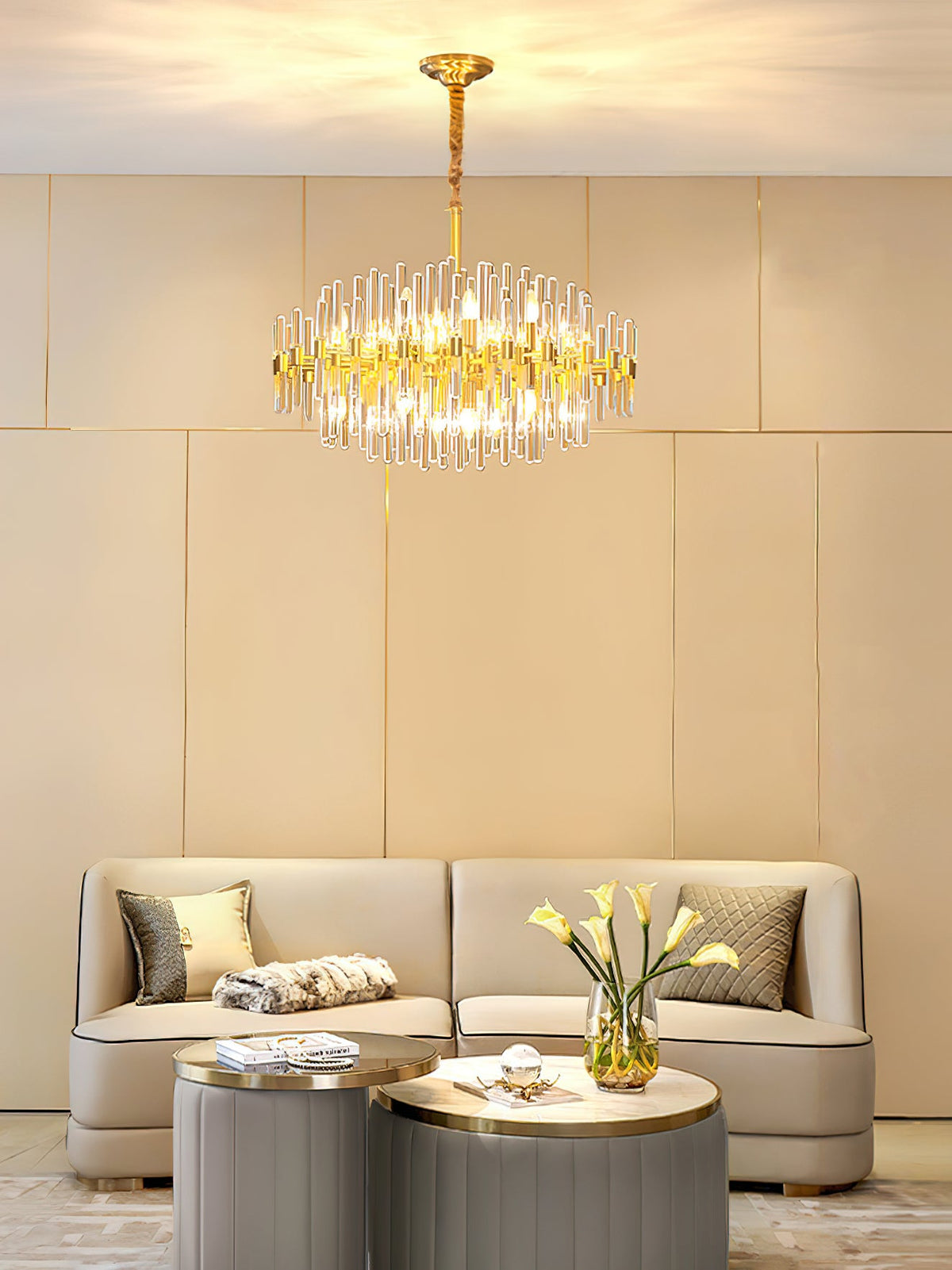 This Clérachic chandelier lit above a round coffee table and cream sofa, with calla lilies on a low table and a wall of cream panels.