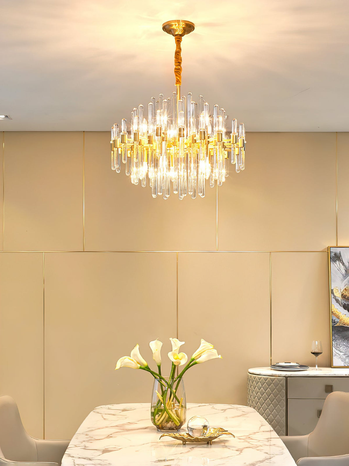 This Clérachic chandelier lit above a dining table with a marble top and calla lilies, in a room with cream panelled walls.