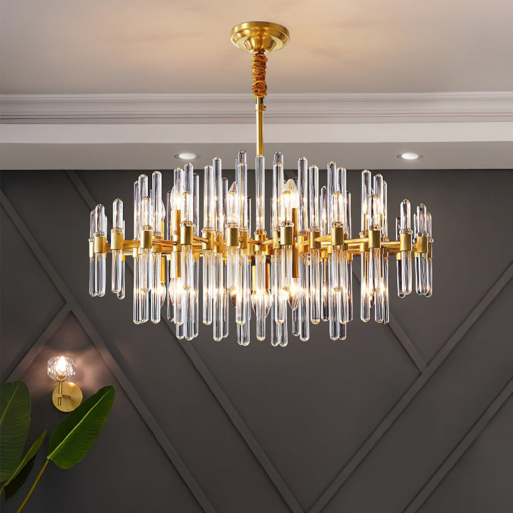 A Clérachic chandelier lit on a dark grey wall with diamond panelling, with a brass wall light and a leaf in the lower corner.