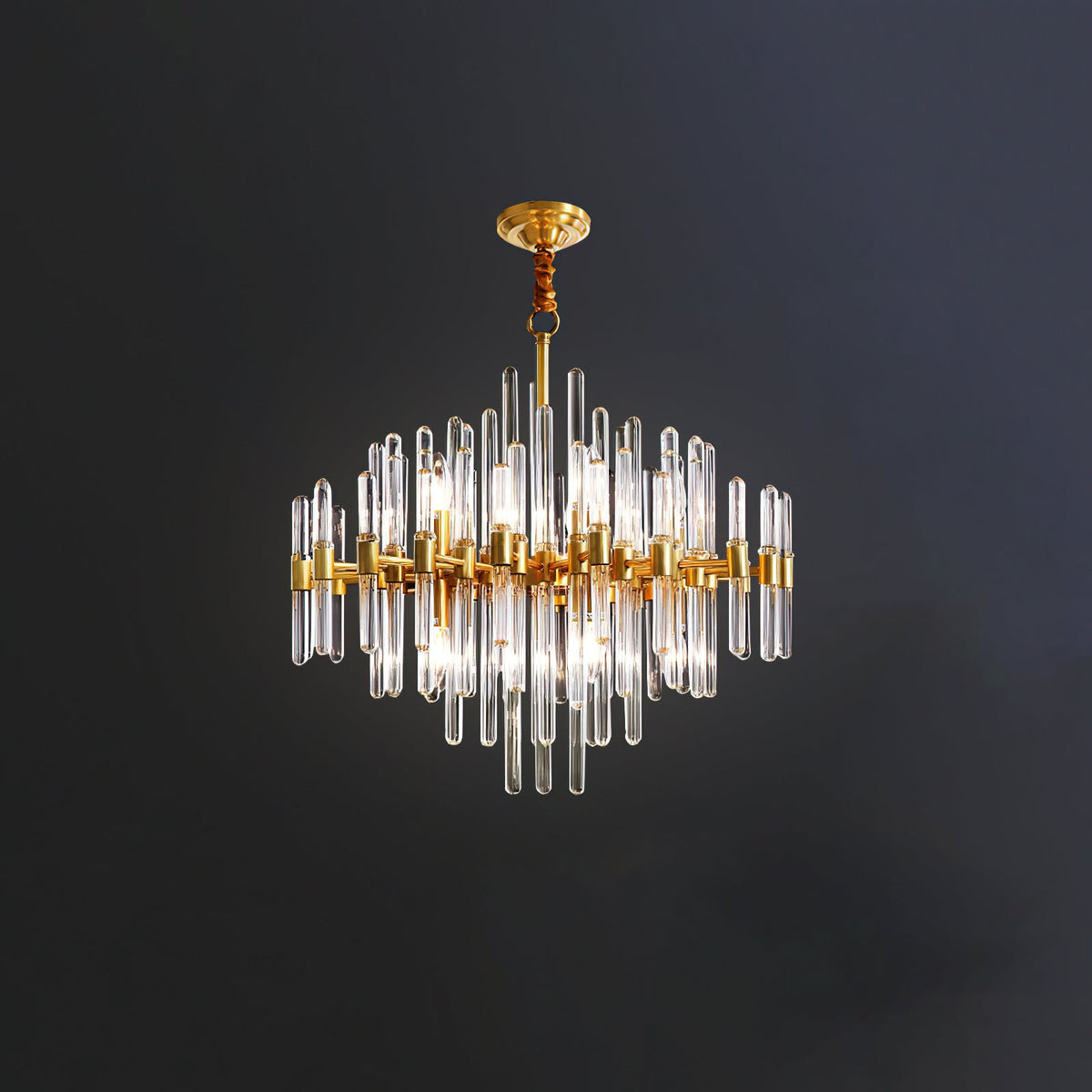A Clérachic chandelier on a short rod against a dark wall, its brass frame holding clear glass rods of varied lengths.