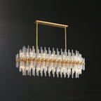 The linear-bar Clérachic chandelier lit on a dark backdrop, with its oval layout and long glass rods in staggered rows.