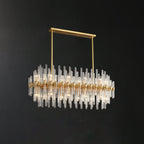 This Clérachic chandelier hangs from a brass bar and two rods, the oval ring of glass rods catching light against a dark wall.