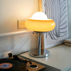 Lit on a white shelf beside a record player, this Clérachic table lamp glows warm from its amber glass shade and white globe.