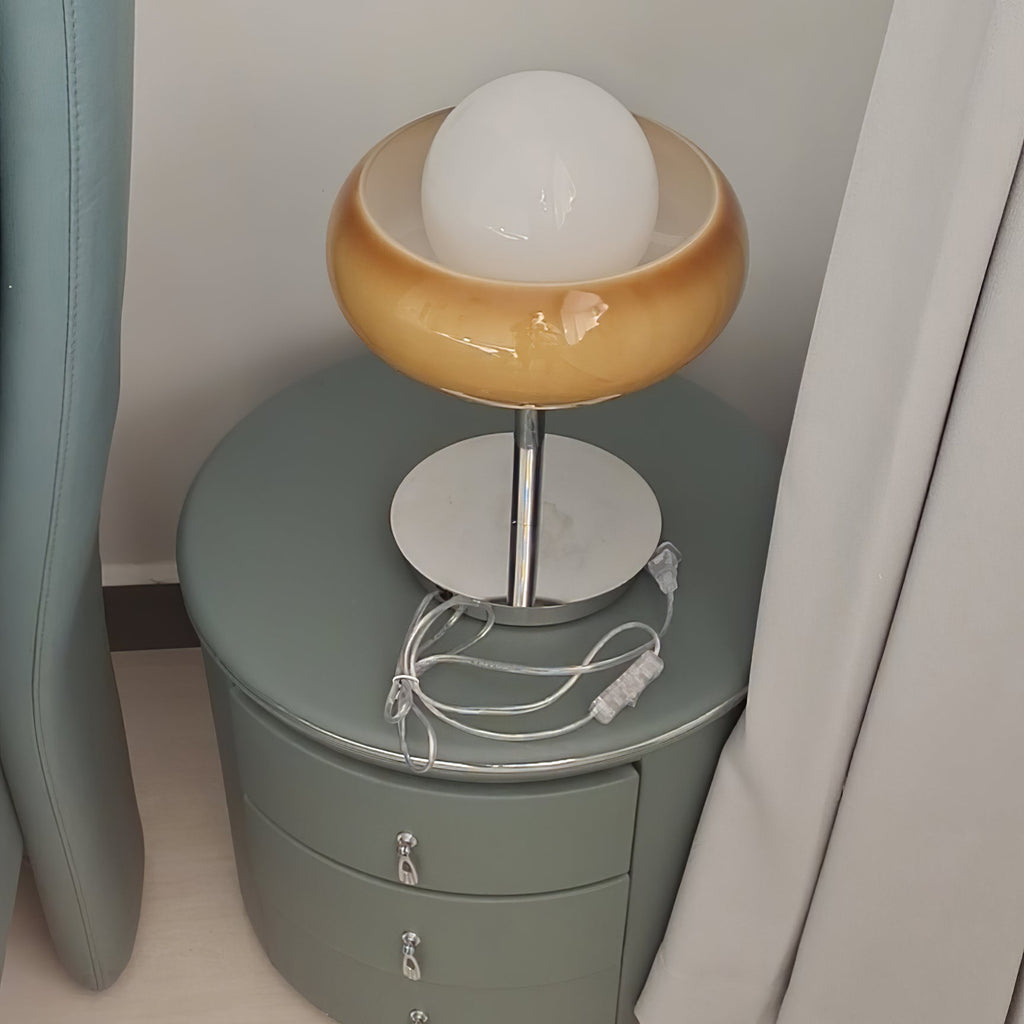 Seen from above on a green round nightstand, this Clérachic table lamp shows its white globe in the amber bowl and the cord below.