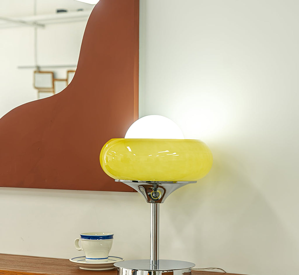 Here this Clérachic table lamp glows lemon yellow in front of a mirror, with a blue-rimmed cup on a saucer beside the base.