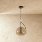 Clérachic pendant light with a smoked amber glass globe and chrome stem, hanging low against a plain plaster wall.