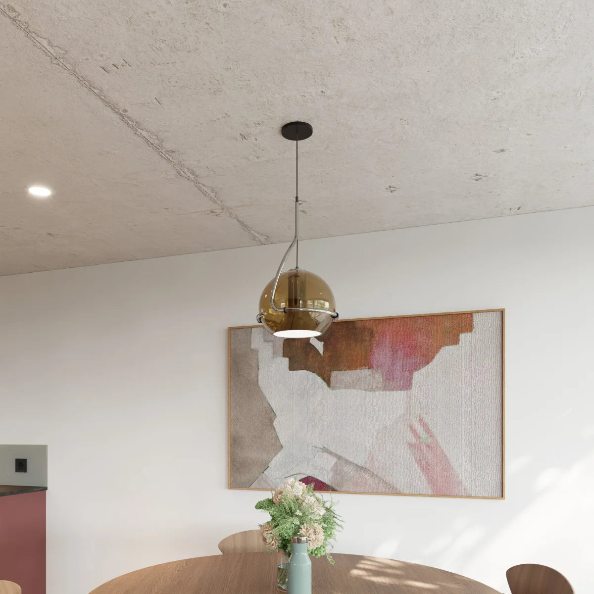 Clérachic champagne glass pendant light hangs beside an abstract painting, its globe shade glowing above a dining table.