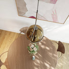 Overhead view of a Clérachic amber glass pendant light above a round wooden dining table set with flowers and chairs.