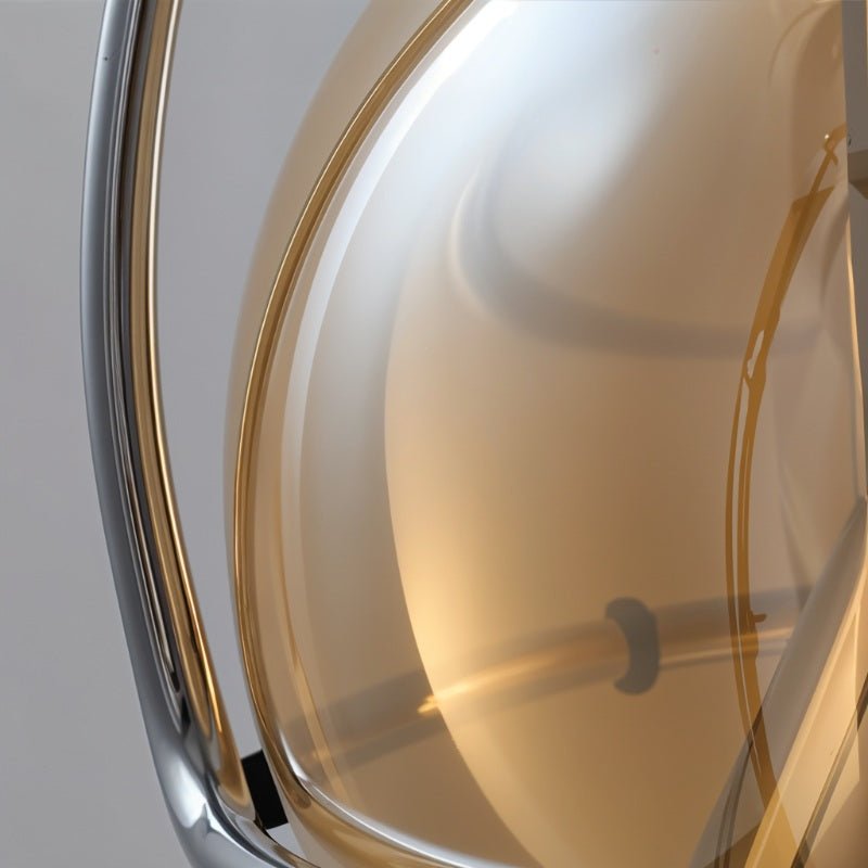Macro detail of the Clérachic pendant's smoked amber glass and polished chrome trim, showing the curve of the globe shade.