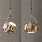Two angles of the Clérachic champagne glass pendant light, chrome arm and ring cradling the globe shade, lit and unlit.