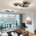 Two Clérachic 6-head Chrome Ceiling Lights over a living room with a white sofa, oak floor, and terrace doors.