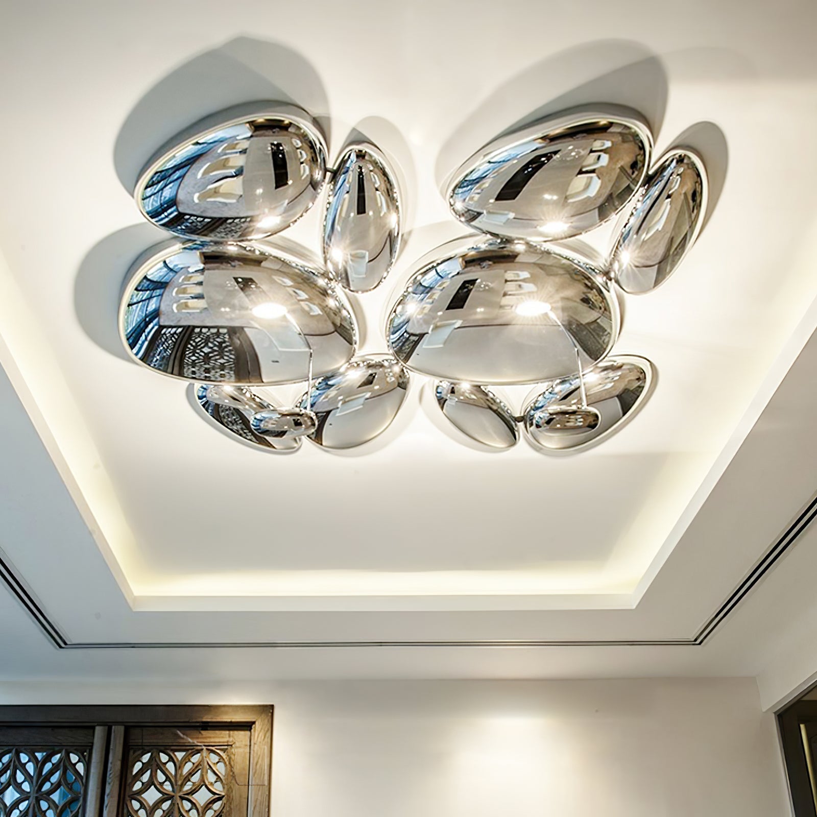 Two Clérachic 6-head Chrome Ceiling Lights on a tray ceiling beside a dark geometric lattice door.