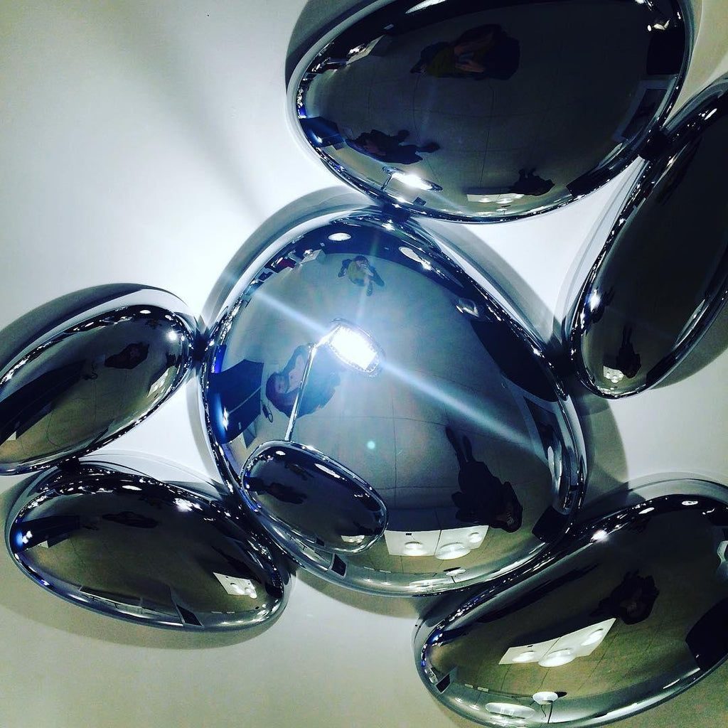 Close-up of the Clérachic 6-head Chrome Ceiling Light, chrome pebbles reflecting a figure under a bright highlight.