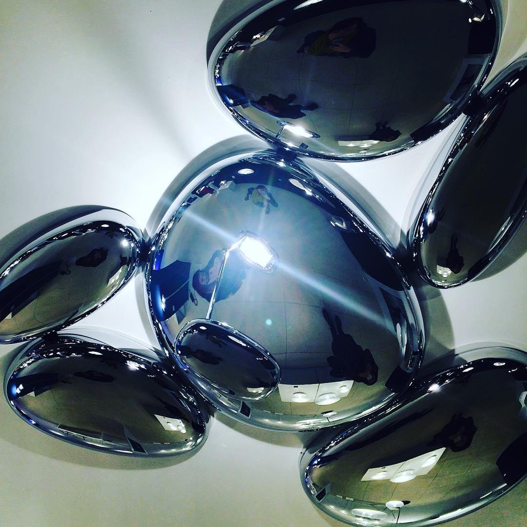 Close-up of the Clérachic 6-head Chrome Ceiling Light, chrome pebbles reflecting a figure under a bright highlight.