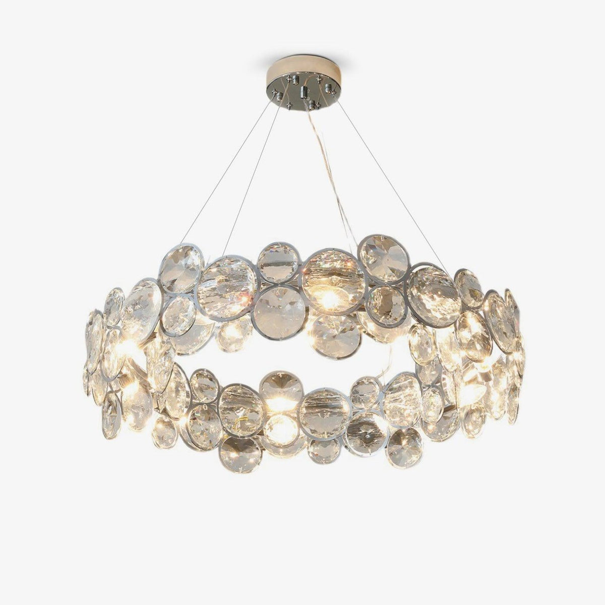 Round Clérachic chandelier with overlapping clear crystal discs in chrome rings, hung on fine cables on a white backdrop.