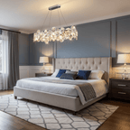 Oval Clérachic crystal chandelier above a tufted headboard bed with blue cushions and a geometric rug.
