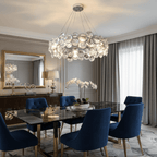 Round Clérachic chandelier over a black marble dining table with navy velvet chairs and a gilt mirror behind.