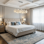 Oval Clérachic crystal chandelier above a bed with a buttoned headboard, a blue patterned rug and tall windows.