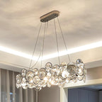 Oval Clérachic crystal chandelier seen from below, with the long chrome canopy and the cove light on the ceiling.