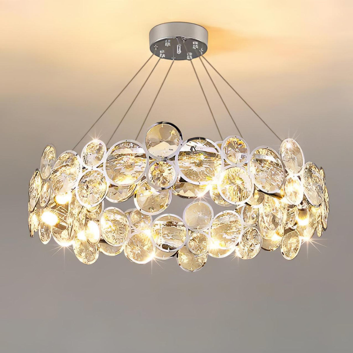 Front view of the lit round Clérachic chandelier, with its two bands of chrome-rimmed crystal discs.