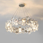 Round Clérachic crystal chandelier on a round chrome canopy, glowing warm against a pale grey wall.