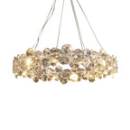 Lit round Clérachic crystal chandelier on thin cables, cut out on a plain white background.