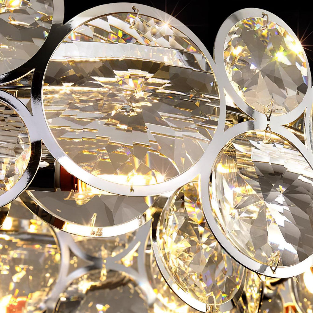 Close view of a large faceted crystal disc held in a polished chrome ring on this Clérachic chandelier.