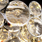 Close view of a large faceted crystal disc held in a polished chrome ring on this Clérachic chandelier.