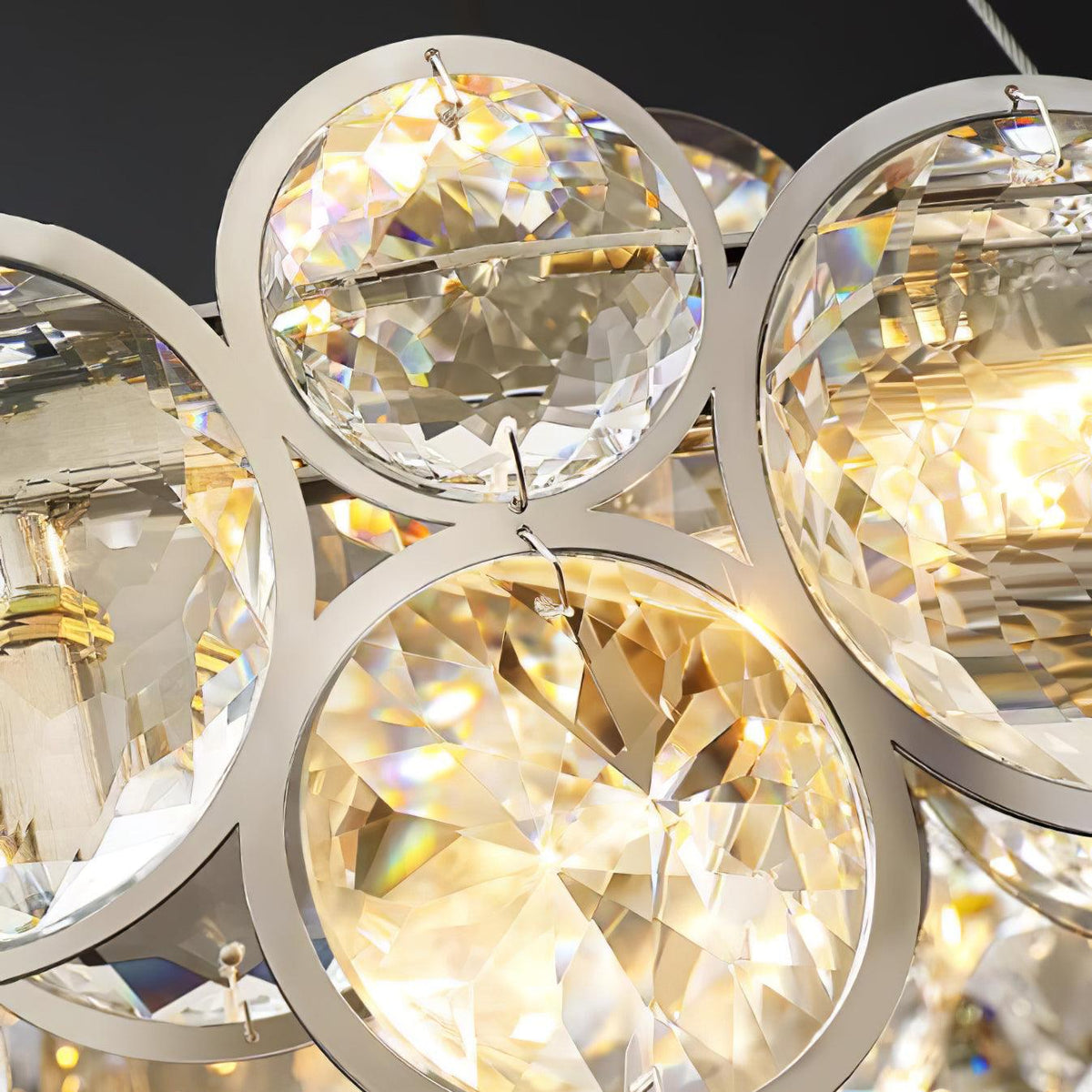 Close view of faceted crystal discs and their chrome rings, with warm light inside this Clérachic chandelier.