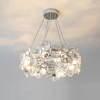 Round Clérachic crystal chandelier with a small chrome canopy, glowing warm against a pale ceiling and wall.