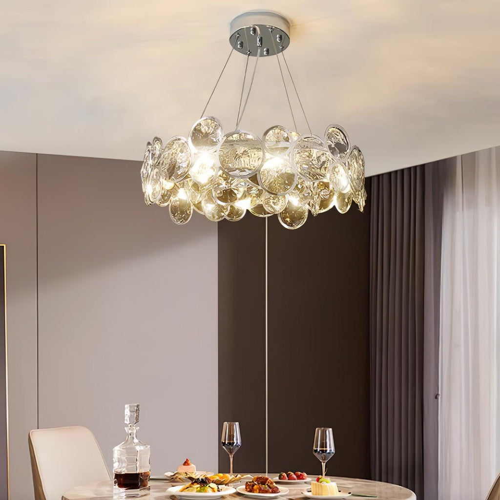 Round Clérachic crystal chandelier above a dining table laid with a decanter, wine glasses and plates of food.