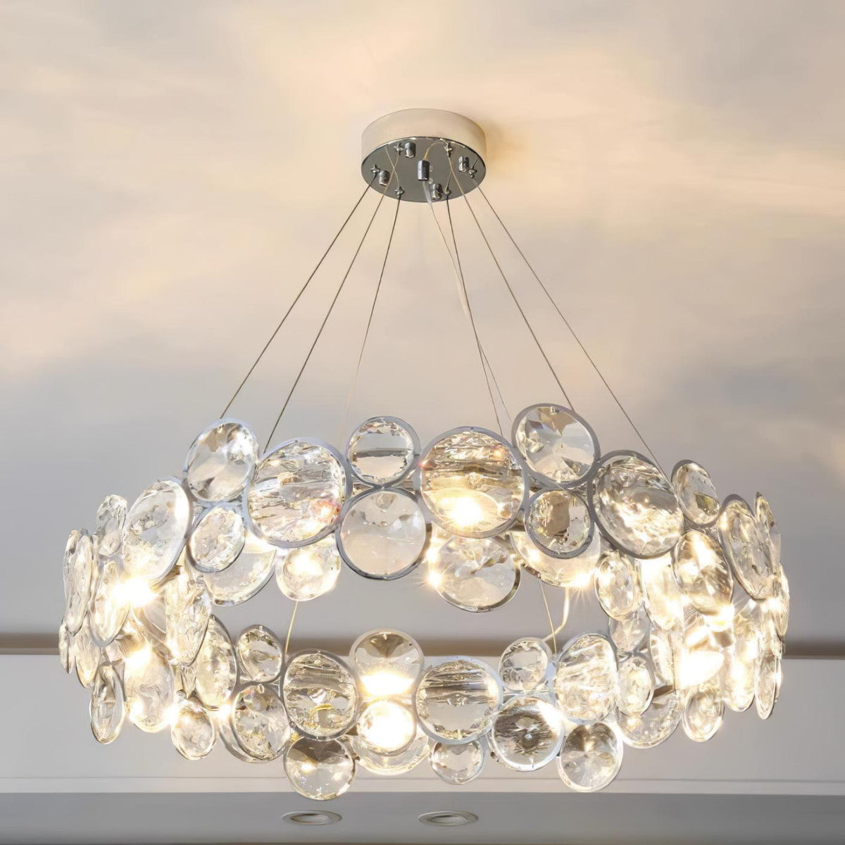 Slightly lower view of the lit Clérachic crystal chandelier, with the glowing bulbs between the clear discs.