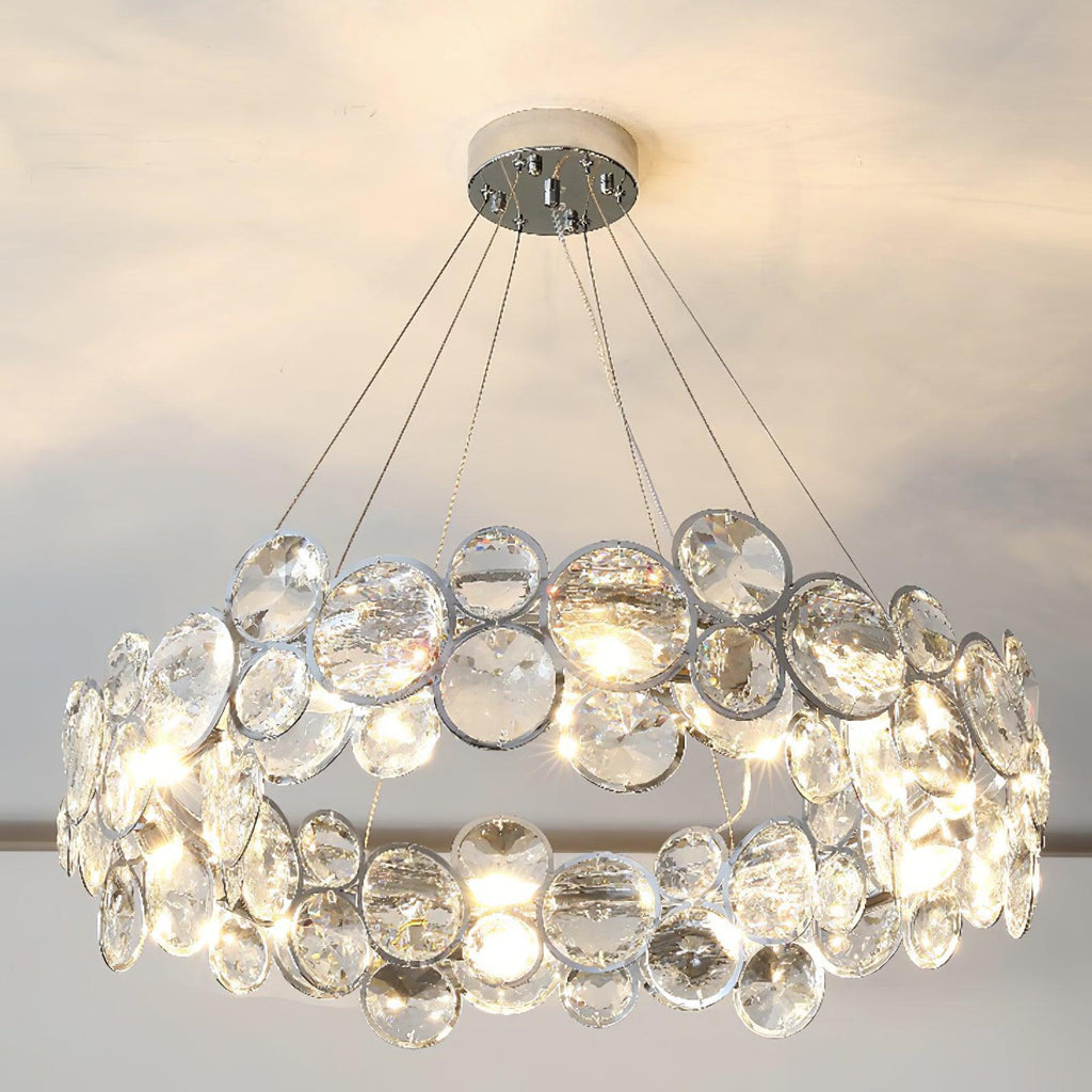 Wide-angle view of the round Clérachic chandelier, with its crystal discs lit warm against a soft cream ceiling.