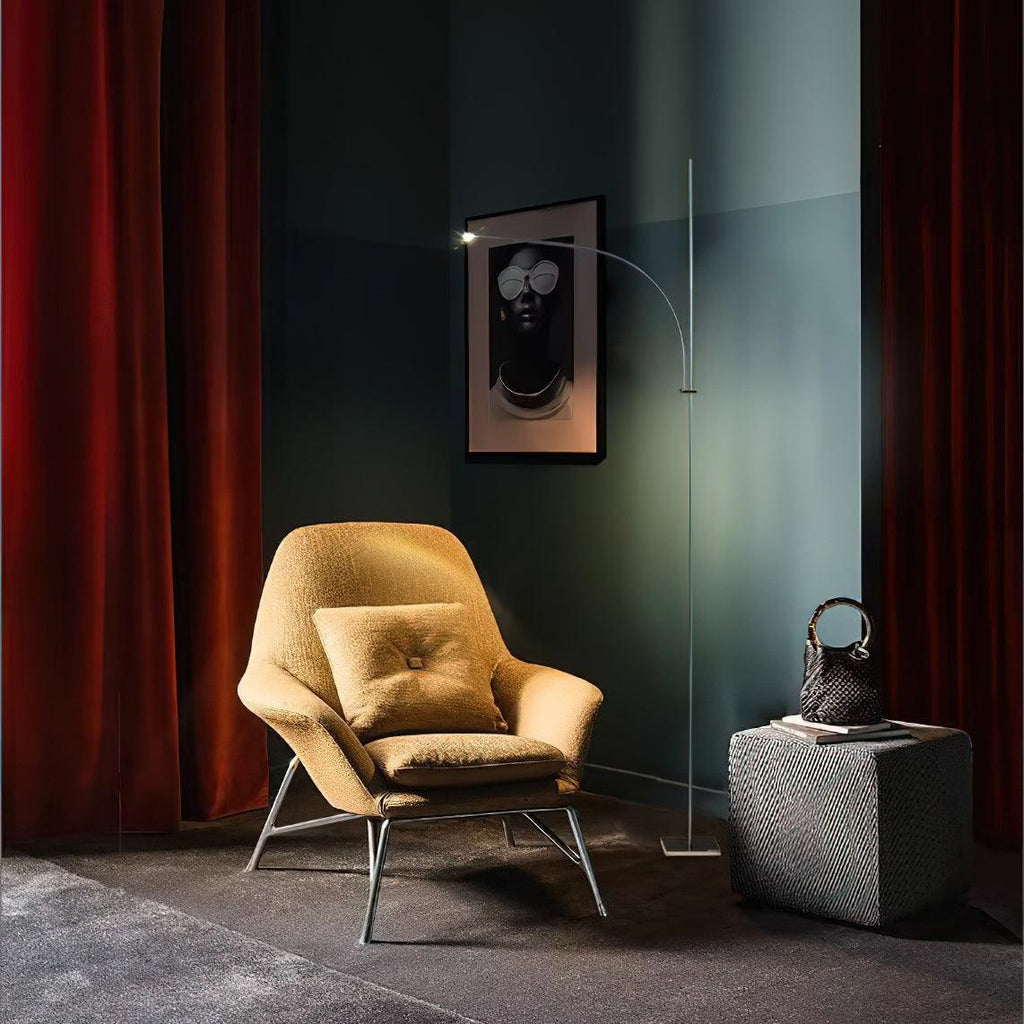 This Clérachic chrome floor lamp stands in a dark teal corner beside a mustard armchair, with red velvet curtains behind.