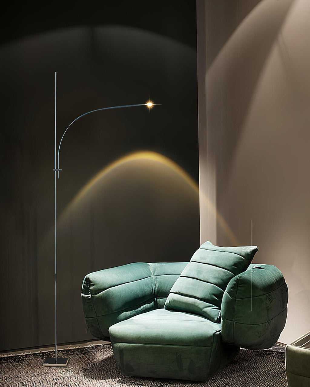 This Clérachic floor lamp stands behind a green velvet armchair, its warm beam rising in an arc up a charcoal wall.