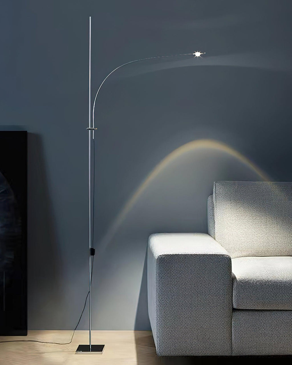 Next to a pale grey sofa on a slate-blue wall, this Clérachic chrome floor lamp casts a warm arched beam.