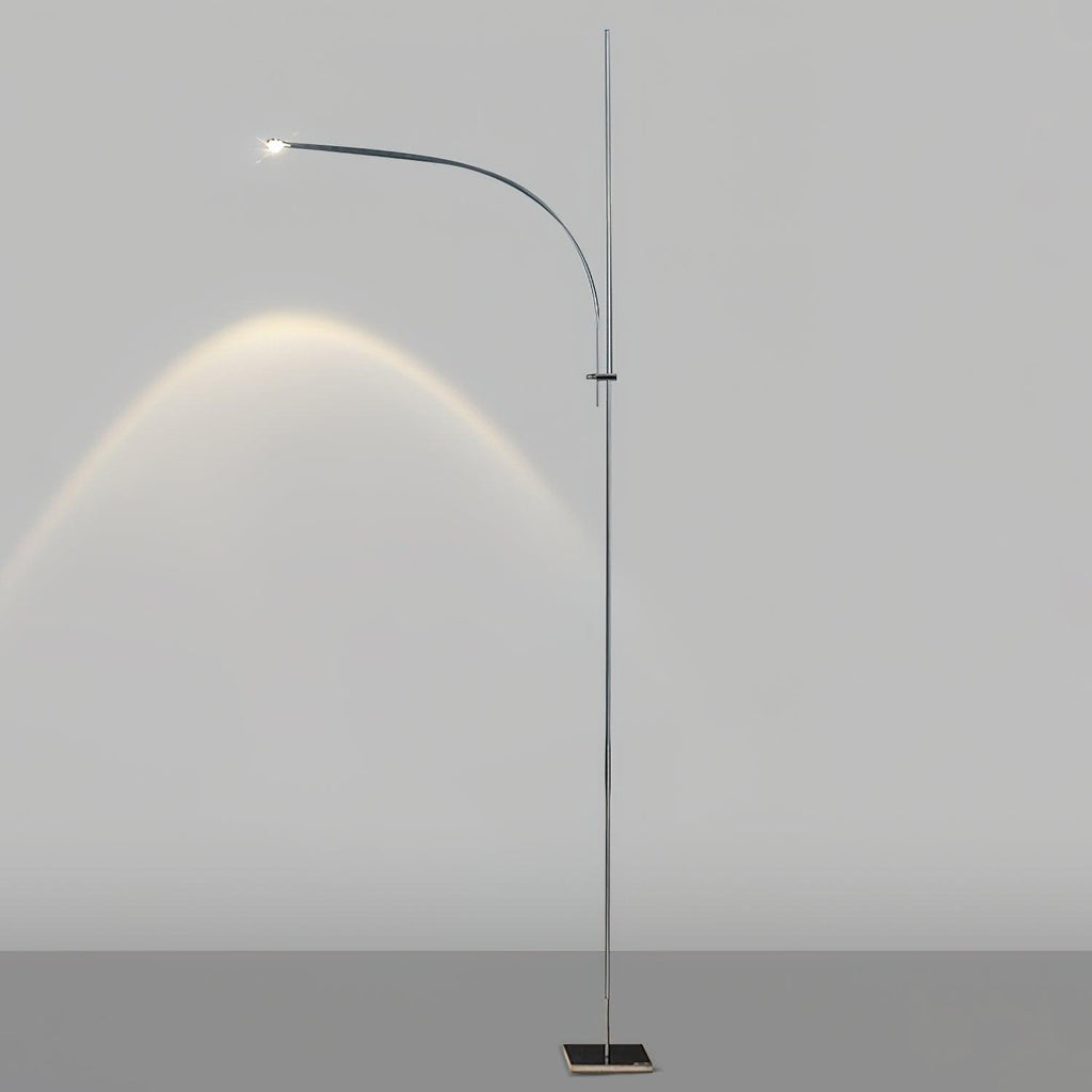 This Clérachic floor lamp on a light grey backdrop, its curved arm casting an arc of warm light on the wall.