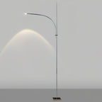 This Clérachic floor lamp on a light grey backdrop, its curved arm casting an arc of warm light on the wall.
