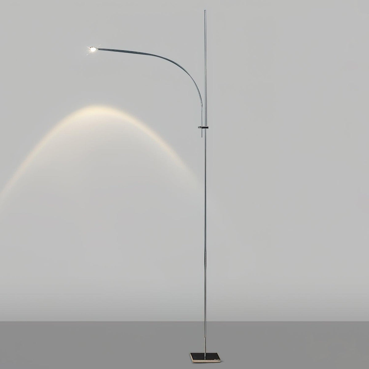 This Clérachic floor lamp on a light grey backdrop, its curved arm casting an arc of warm light on the wall.