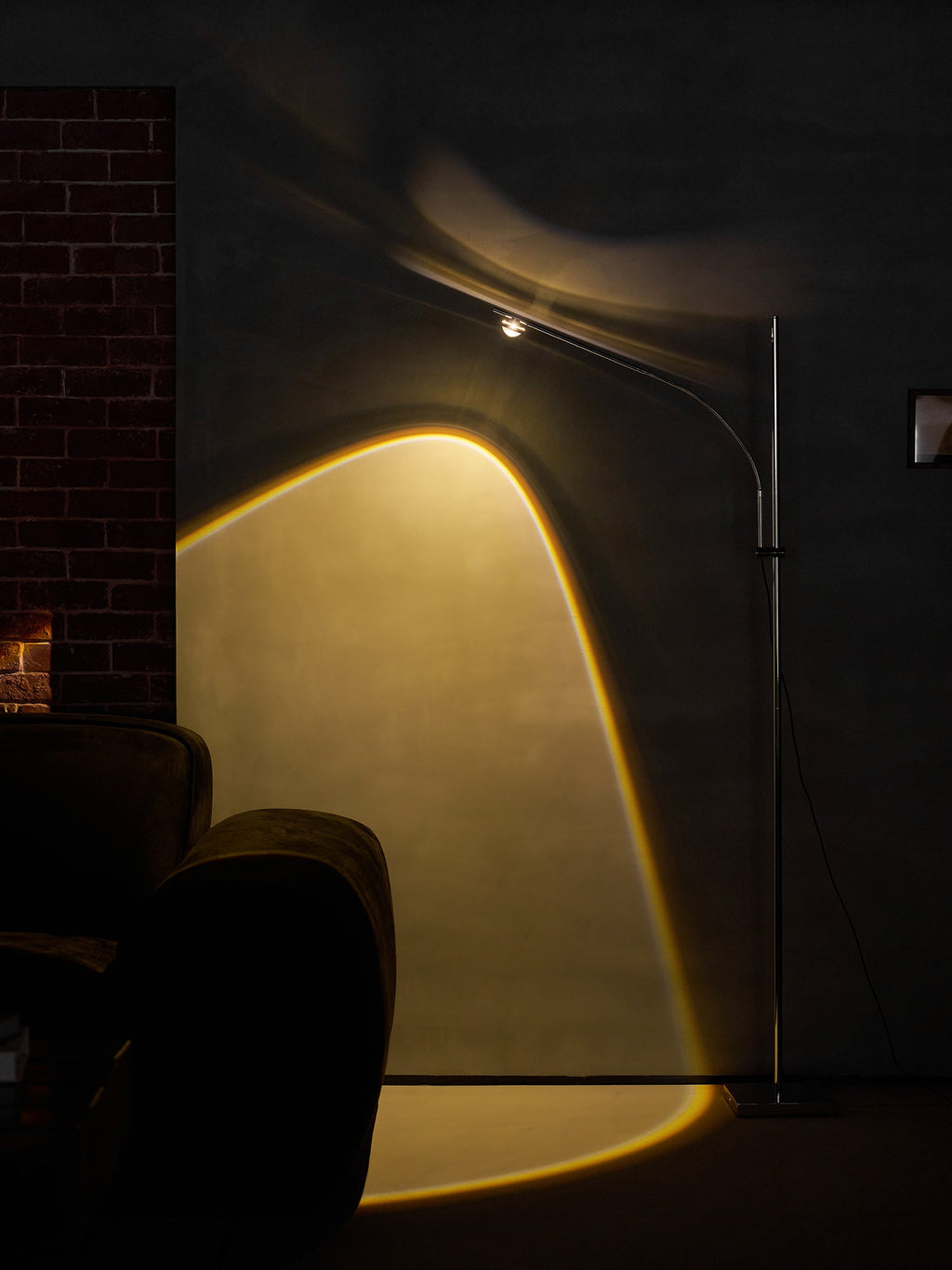 In a dark room with a brick wall, this Clérachic floor lamp casts a bright amber arc across the wall and floor.
