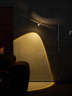 In a dark room with a brick wall, this Clérachic floor lamp casts a bright amber arc across the wall and floor.