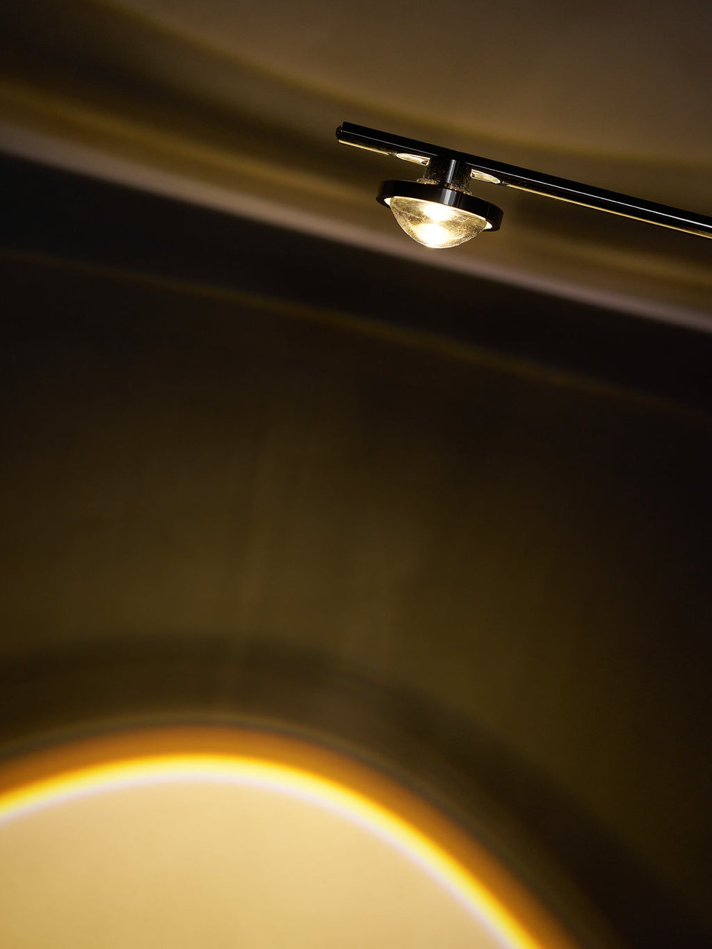 Close view of the small lamp head on this Clérachic floor lamp, with the warm edge of its light beam below.